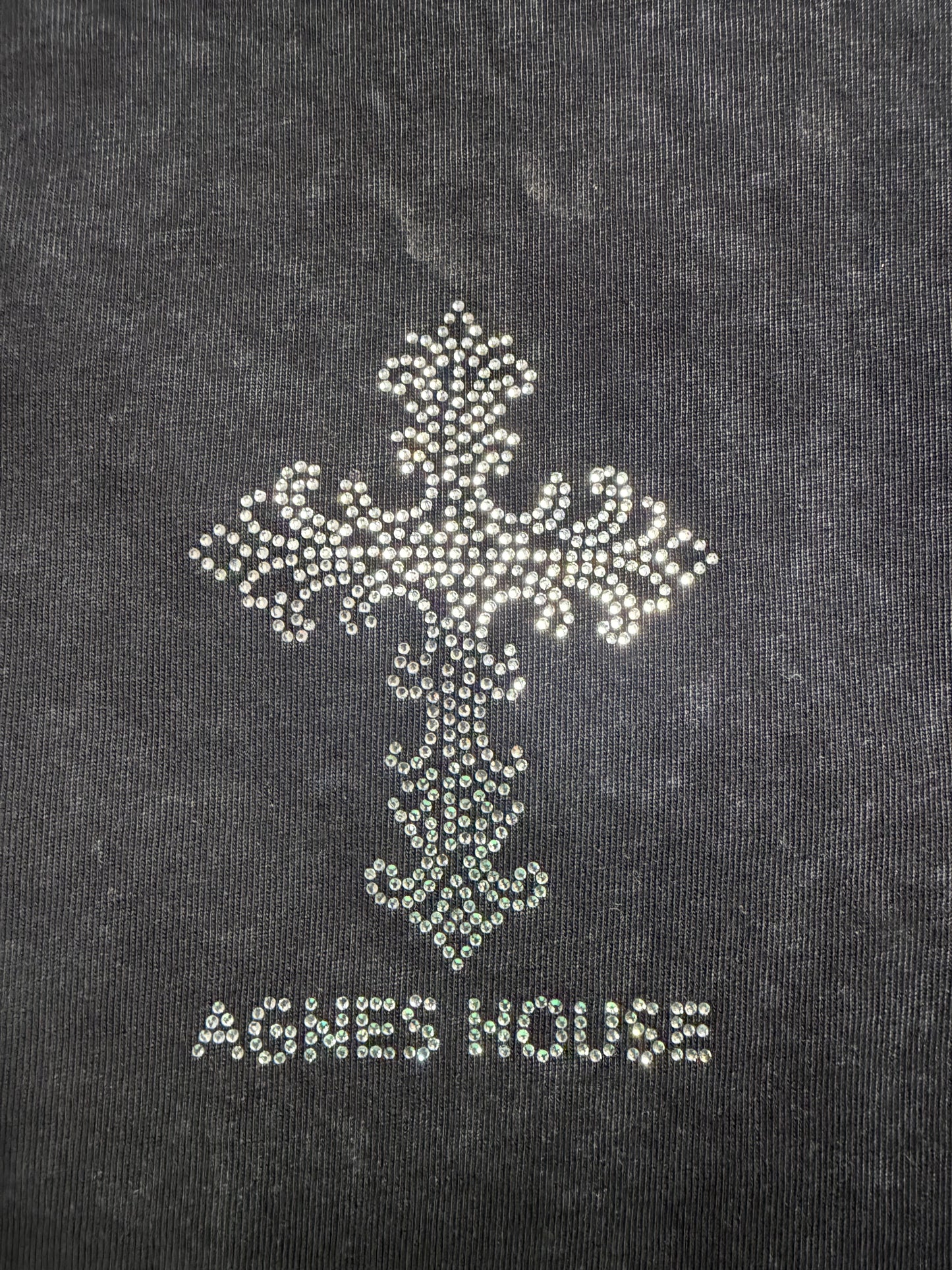 Close-up of large crystal rhinestone cross and Agnes House lettering on the black washed T-shirt