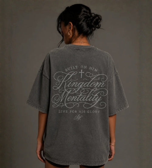 Model wearing a washed gray oversized Kingdom Mentality Christian T-shirt with a faith-inspired back graphic. 